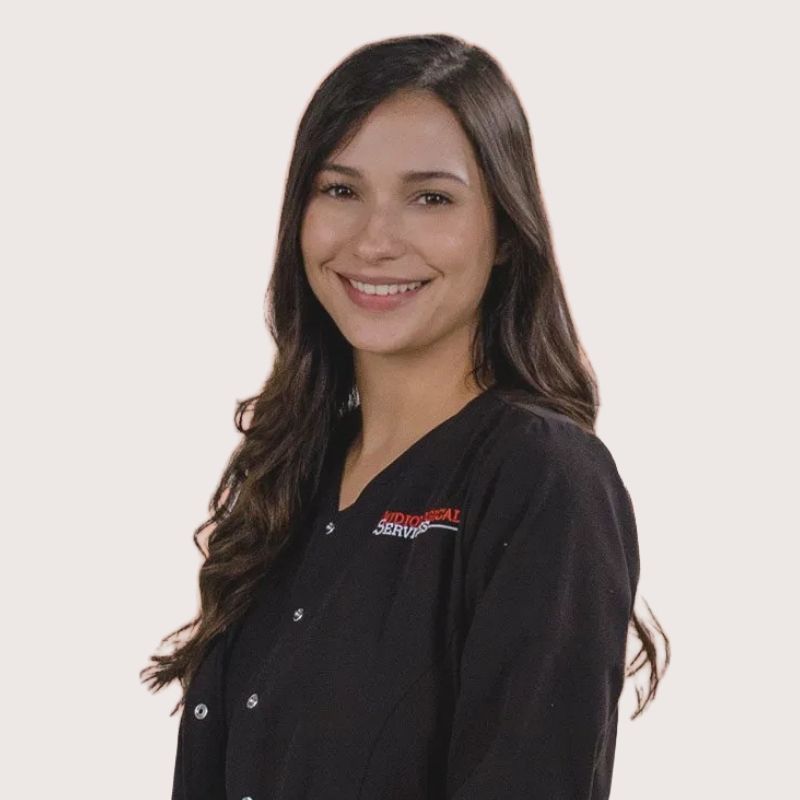 Dr. Gabrielle Tabb, audiologist, smiling with long dark hair in black Audiological Services scrubs
